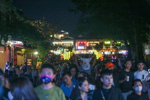 Tourists walk around Hoi An ancient town, waiting in long queues to drop flower lanterns on the Tet holiday